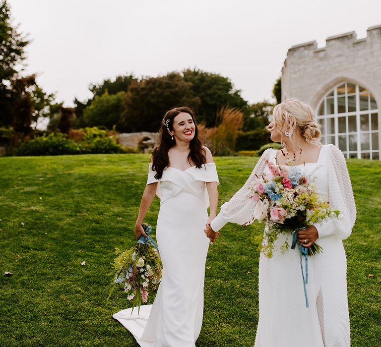 Brides walking hand in hand at castle wedding venue 