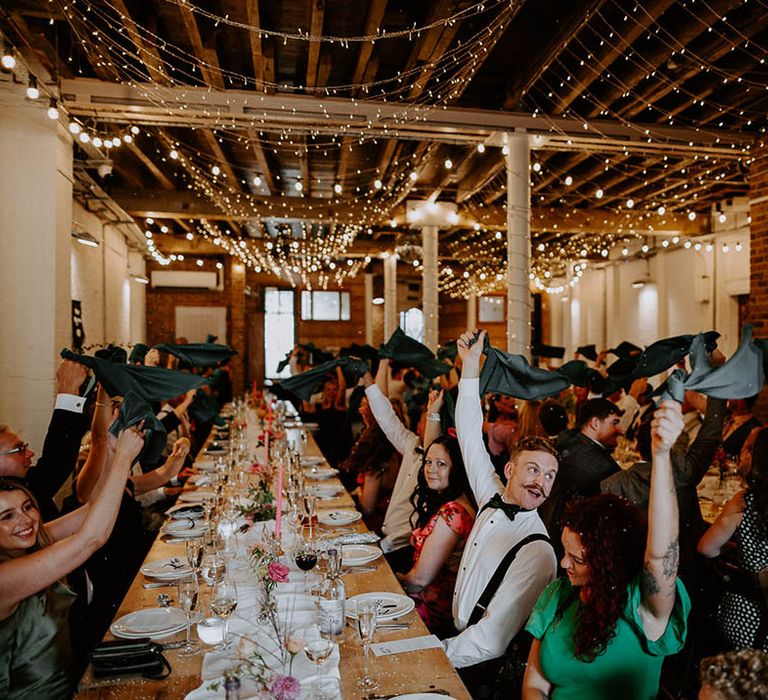 Wedding guests wave their napkins to greet the bride and groom as they enter their wedding reception 