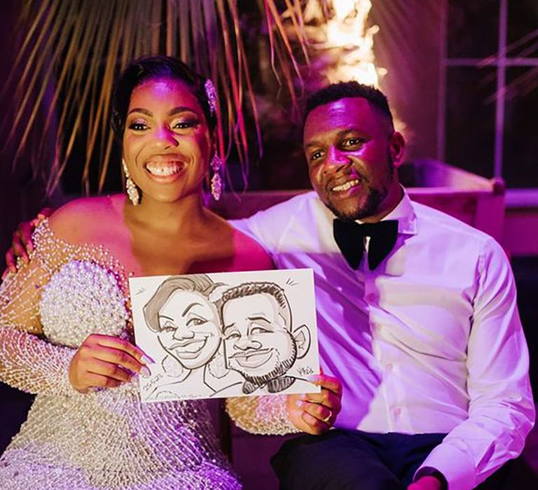 Couple posing with their wedding caricature paintings