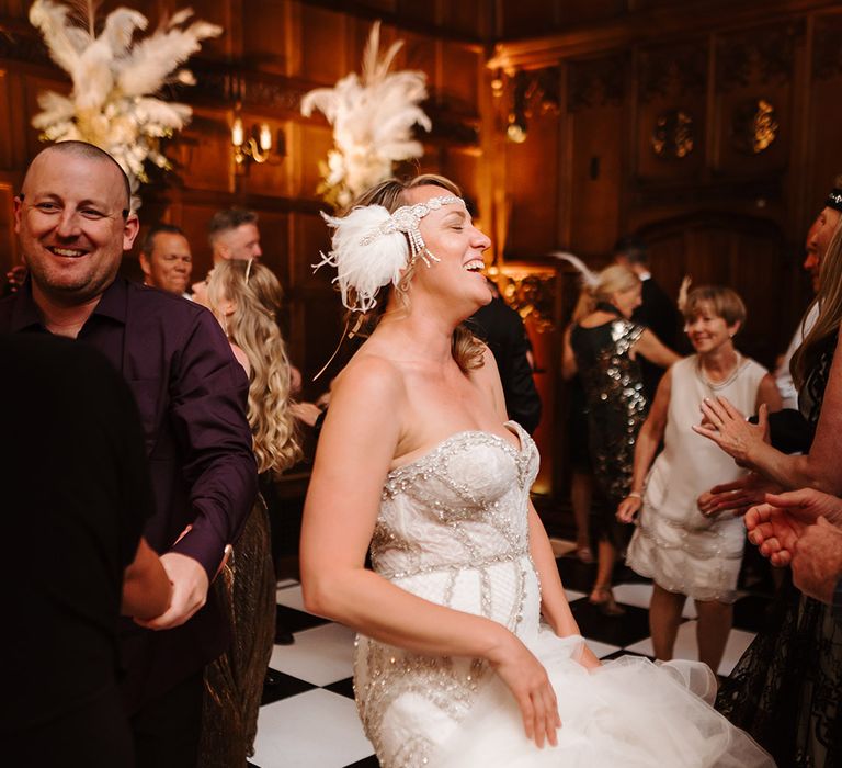 Bride with feather hair accessory headband in strapless mermaid wedding dress by Badgley Mischka dancing at the wedding reception 