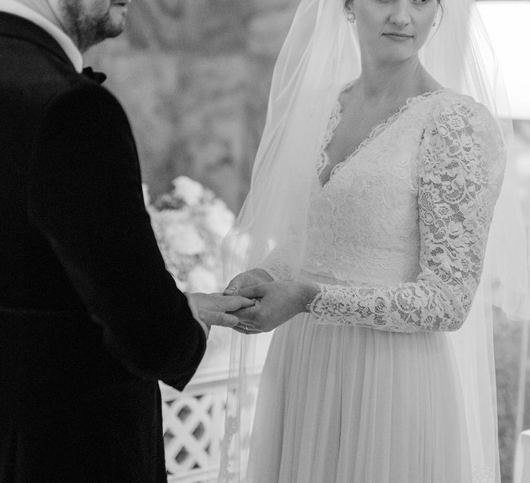 Bride wearing long sleeve wedding dress with the groom at their wedding ceremony 