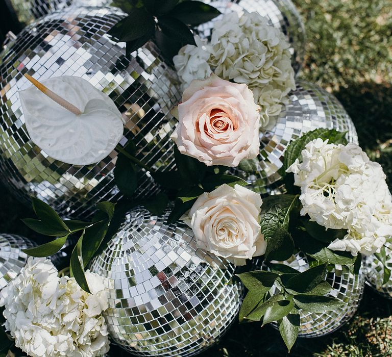 Disco balls with pink and white roses as decoration for the outdoor wedding 