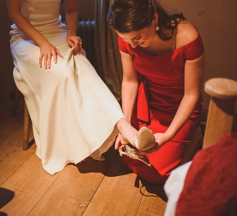 Family member fitting bridal shoes for bride 