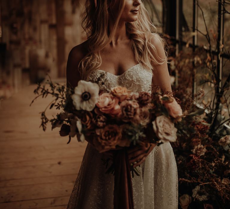 Bride in strapless wedding dress holding a winter wedding bouquet 