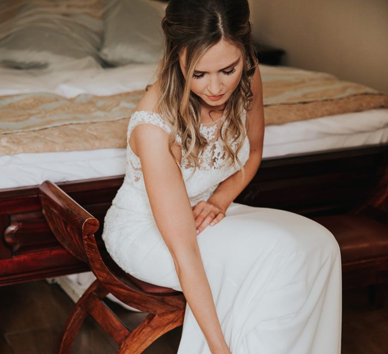 Bride on the wedding morning putting on her bridal shoes 