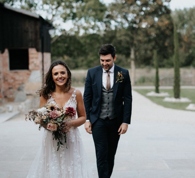 Bride in lace wedding dress and groom in navy suit