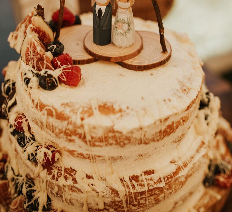 Homemade wedding cake with wooden people topper wearing face masks 