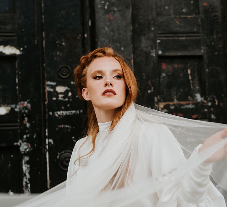 Bride in with red hair in satin two piece and wedding veil 