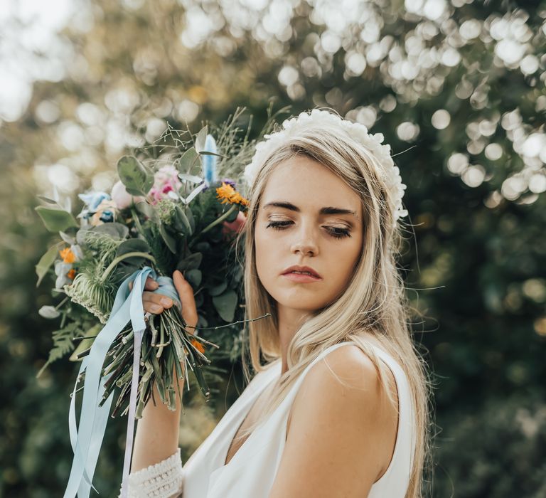 Bride with soft shimmery makeup posing with her bright wedding bouquet