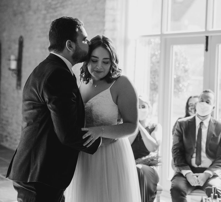 Groom kissing bride at the altar