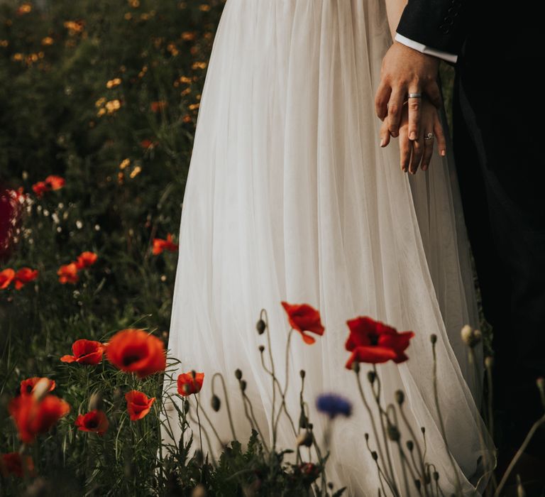 Bride and groom holding hands in wildflower meadow