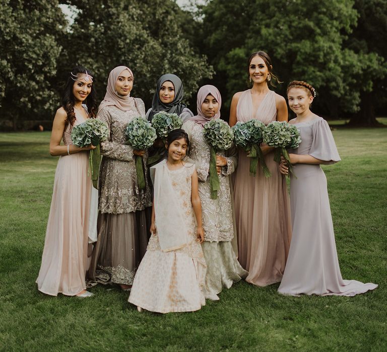 Bridesmaids in pastel grey and pink dresses with green hydrangea bouquets 