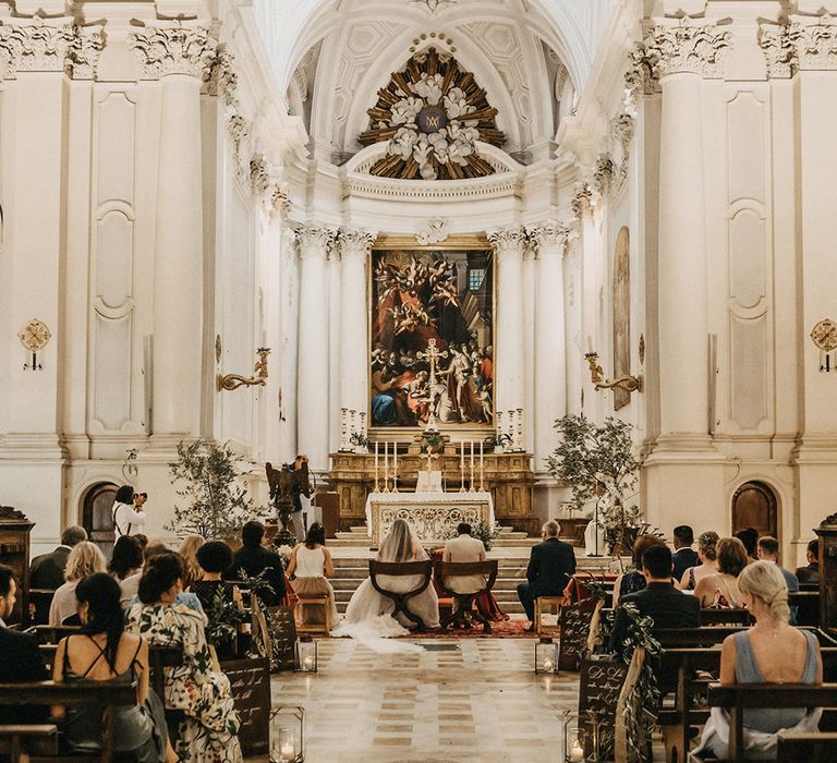 The bride and groom bow their heads as they get married at a Tuscany church