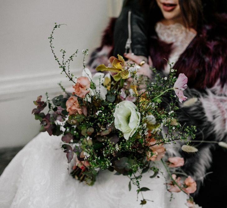 Bride holding bouquet featuring white blooms and green foliage 