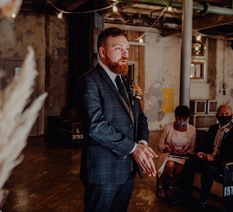 Groom waiting at the altar in a blue wool suit