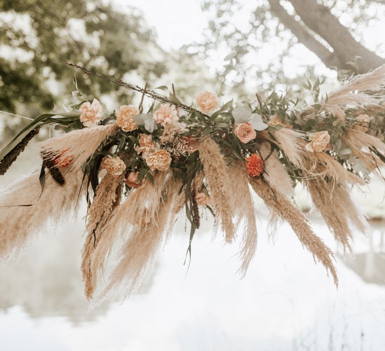 Tied pampas grass with white and orange flowers and green leaf foliage 