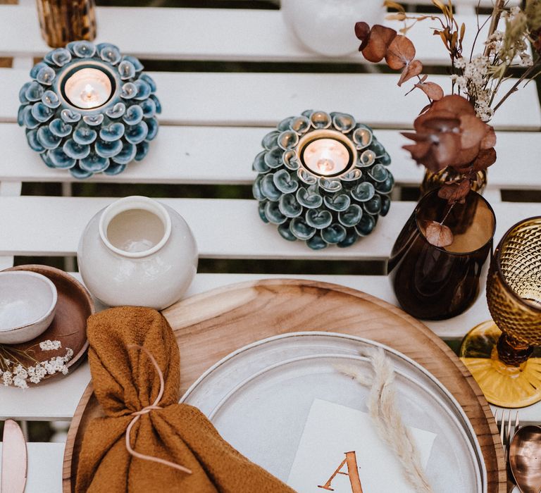 White plates atop wooden placemats with burnt orange napkin 