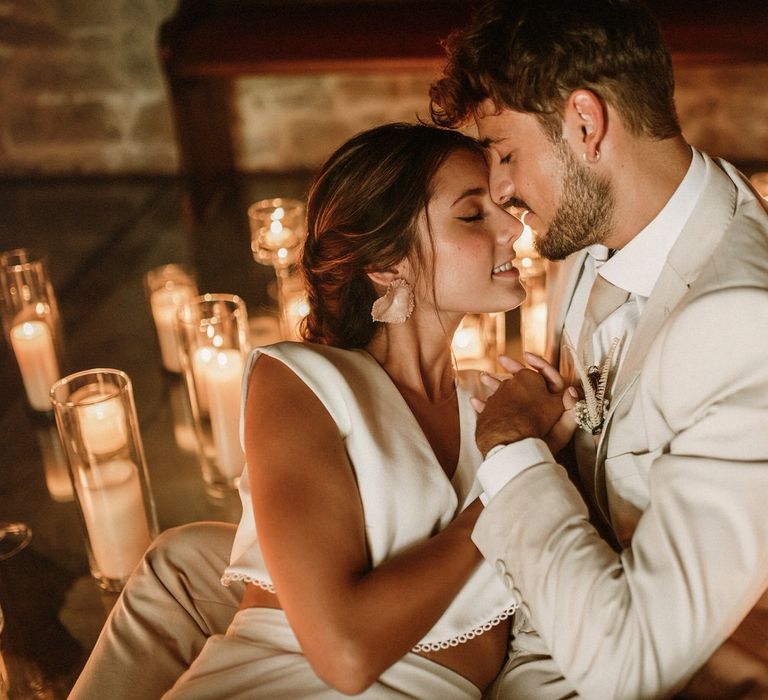 Intimate wedding portrait of a bearded groom in a beige suit holding his brides hand in separates