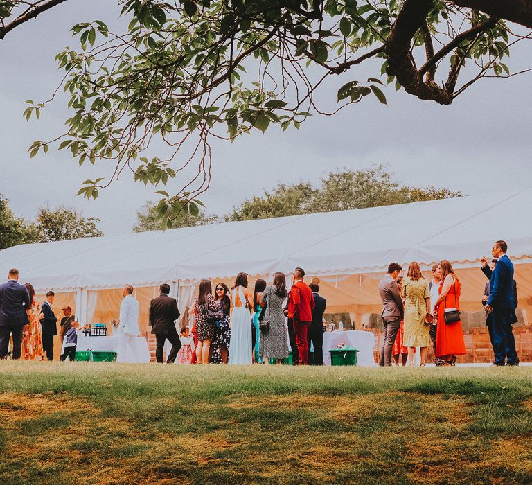 Wedding party gather outside marquee 