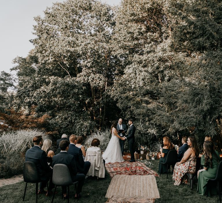 Bride & groom during wedding ceremony stand upon rustic rug