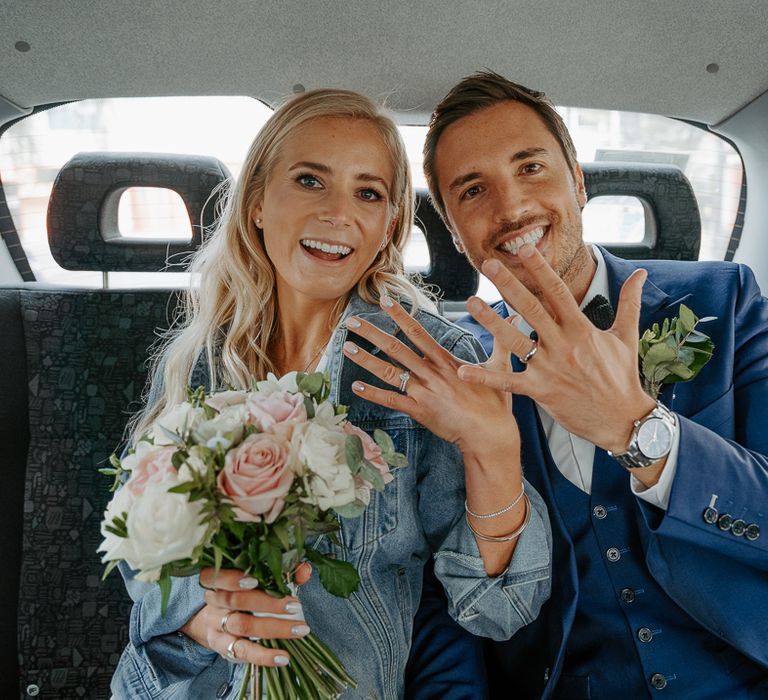 Bride & groom show their wedding rings in wedding car