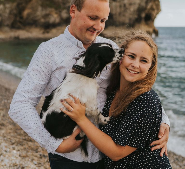 Bride and groom to be holding dog on Dorset beach Durdle door bay 