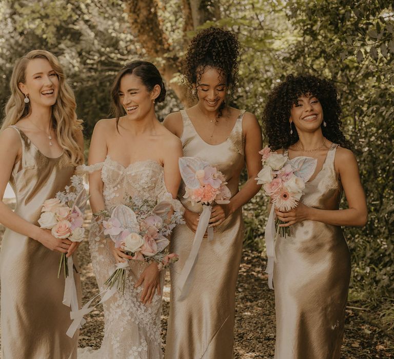 Bride in a fitted appliqué wedding dress and bridesmaids in satin slip dresses 