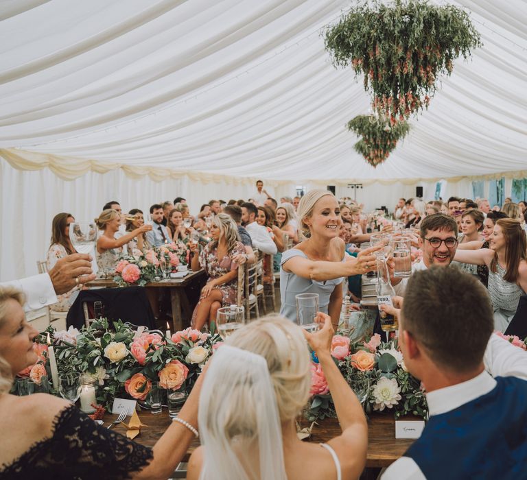 Bride & groom stand in front of their wedding guests in marquee garden wedding reception