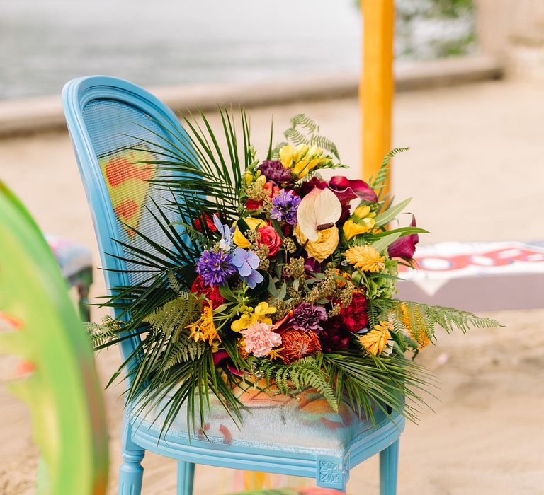 Colour bouquets sits upon bright blue chair with Superman Print