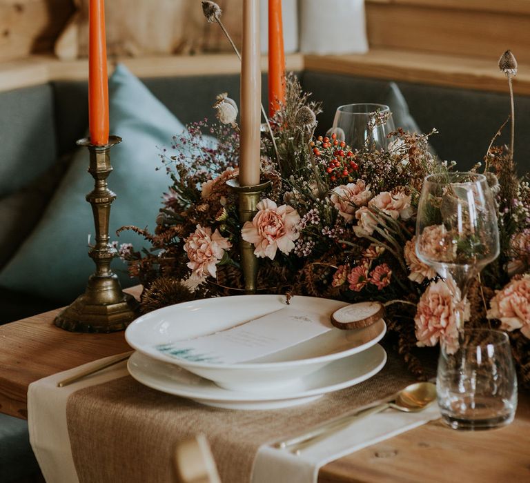 Place setting with orange taper candles, wood name place and dried flower centrepiece decor