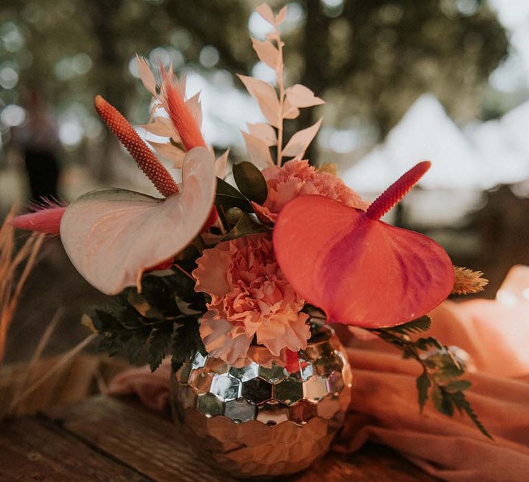 Mini disco ball vase with pink and green tropical floral bouquet on wooden table at festival themed wedding