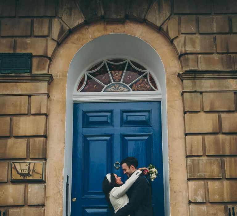 Bride and groom kissing outside blue door at bath wedding