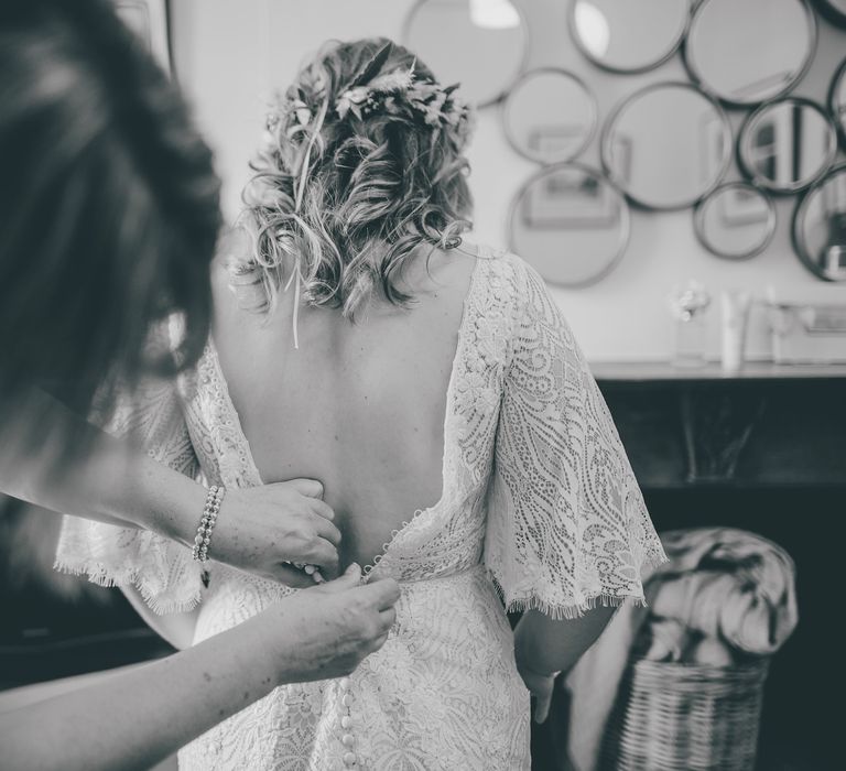 Bride has her gown done up by friend in black & white image