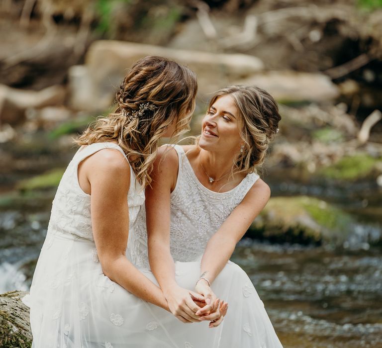 Brides sit together and look lovingly at one another on their wedding day