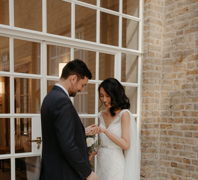 Groom holding up the bride's hand to look at her wedding ring