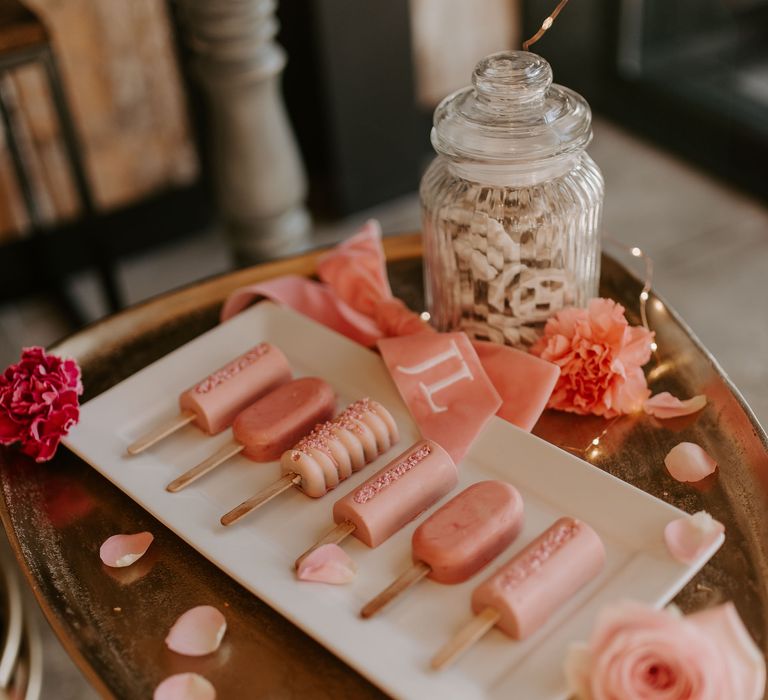 Pink cake pops on a white plate at wedding dessert table 