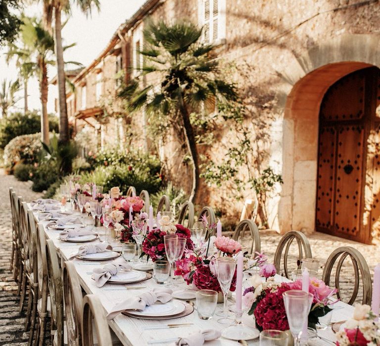 Pink tapered candles with pink peonies and deep fuchsia hydrangea flowers on a white and pink banquet tablescape