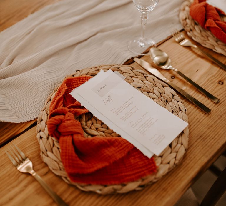 Wedding table place setting with orange linen napkins