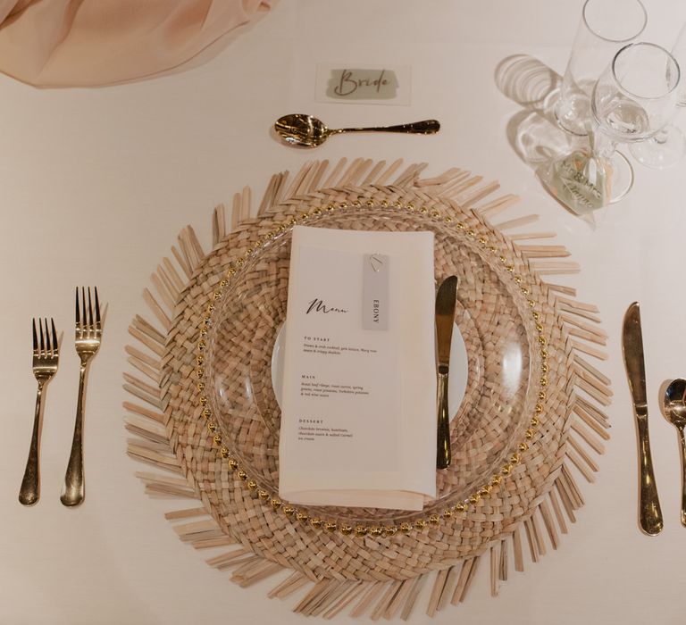 Place setting with wicker placemat, gold rimmed charger plate and gold cutlery