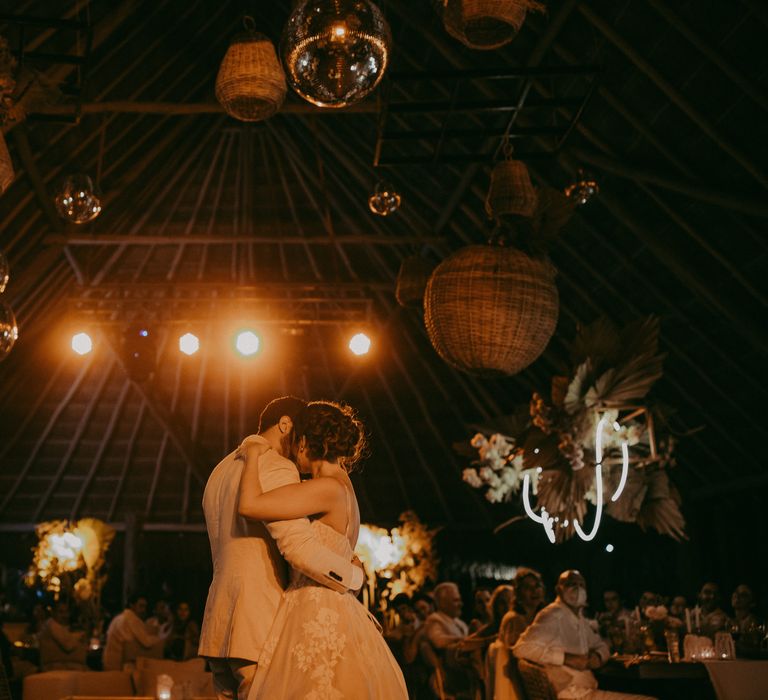 Bride & groom stand with one another on their wedding day during reception as the lights shine around them