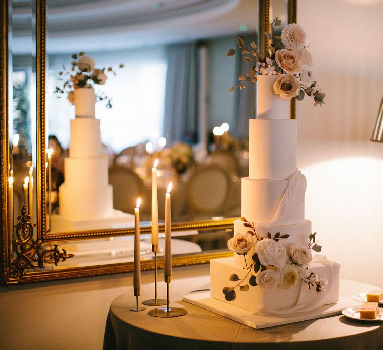 Tall wedding cake with square base and round layers decorated in iced flowers