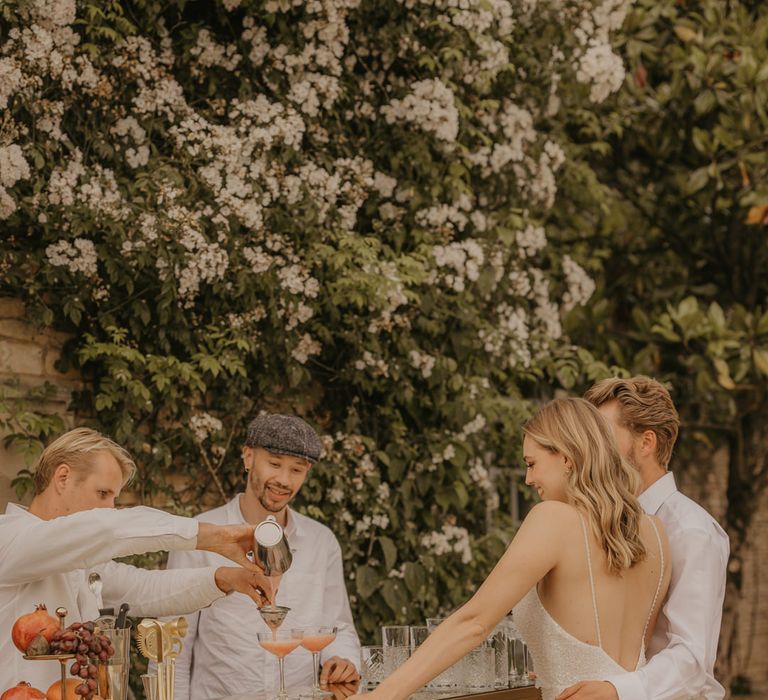 Bride in an embellished Made With Love dress standing at the outdoor mobile bar with her husband in a beige suit 