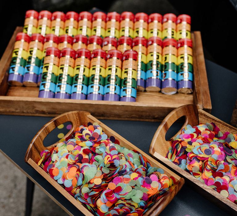 Wooden trays full of multicoloured circular confetti and confetti canons on black table outside for wedding at Loft Studios London