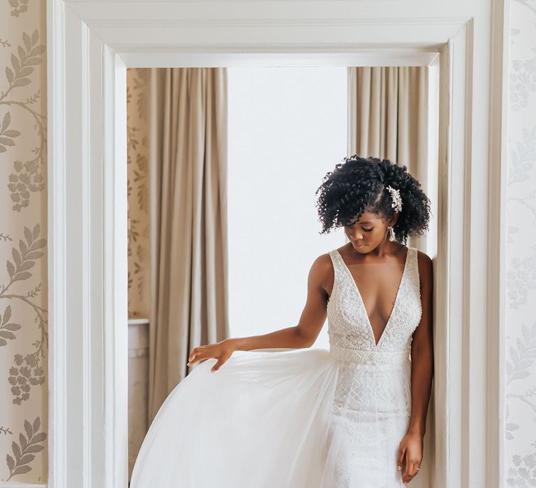 Black bride with naturally curly hair in a plunging neckline wedding dress with tulle skirt 