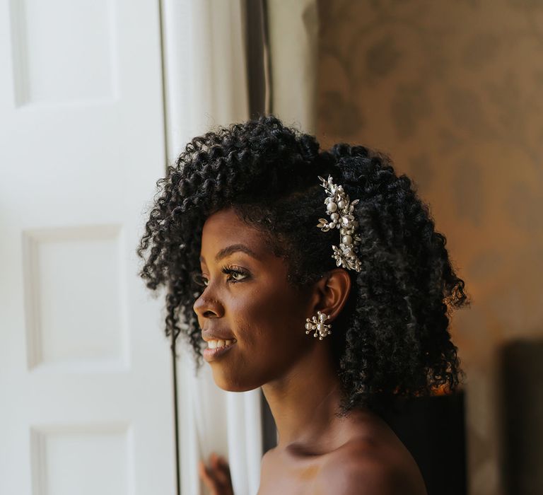 Black bride in a strapless wedding dress with naturally curly afro hair side swept and styled with a jewel hair slide 