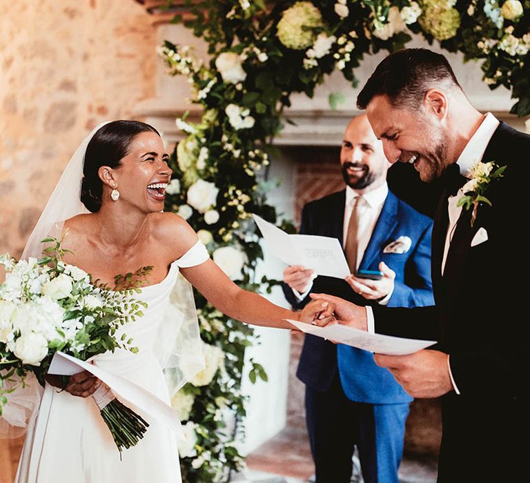 Bride & groom laugh with one another during ceremony on their wedding day