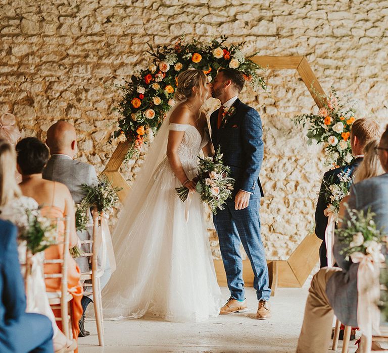 Bride and groom at East Afton Farmhouse wedding with orange flower decor