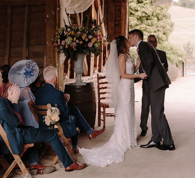 Bride and groom kiss at White Pond Farm barn wedding ceremony