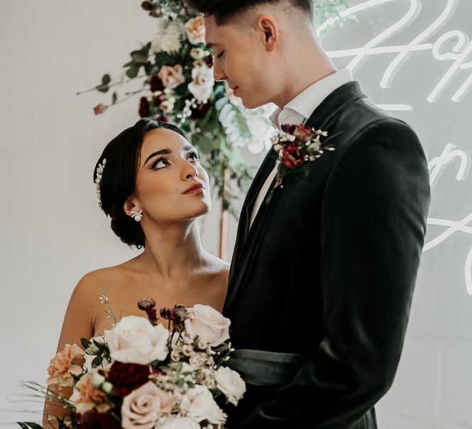 Bride & groom look lovingly at one another as she holds floral bouquet