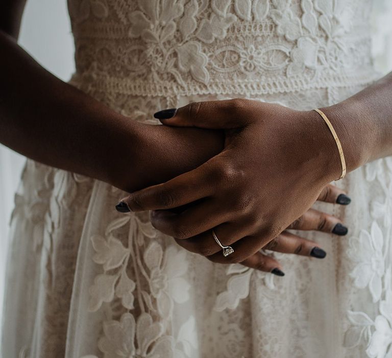 Close up of the fine detailed embroidered wedding dress with diamond wedding ring